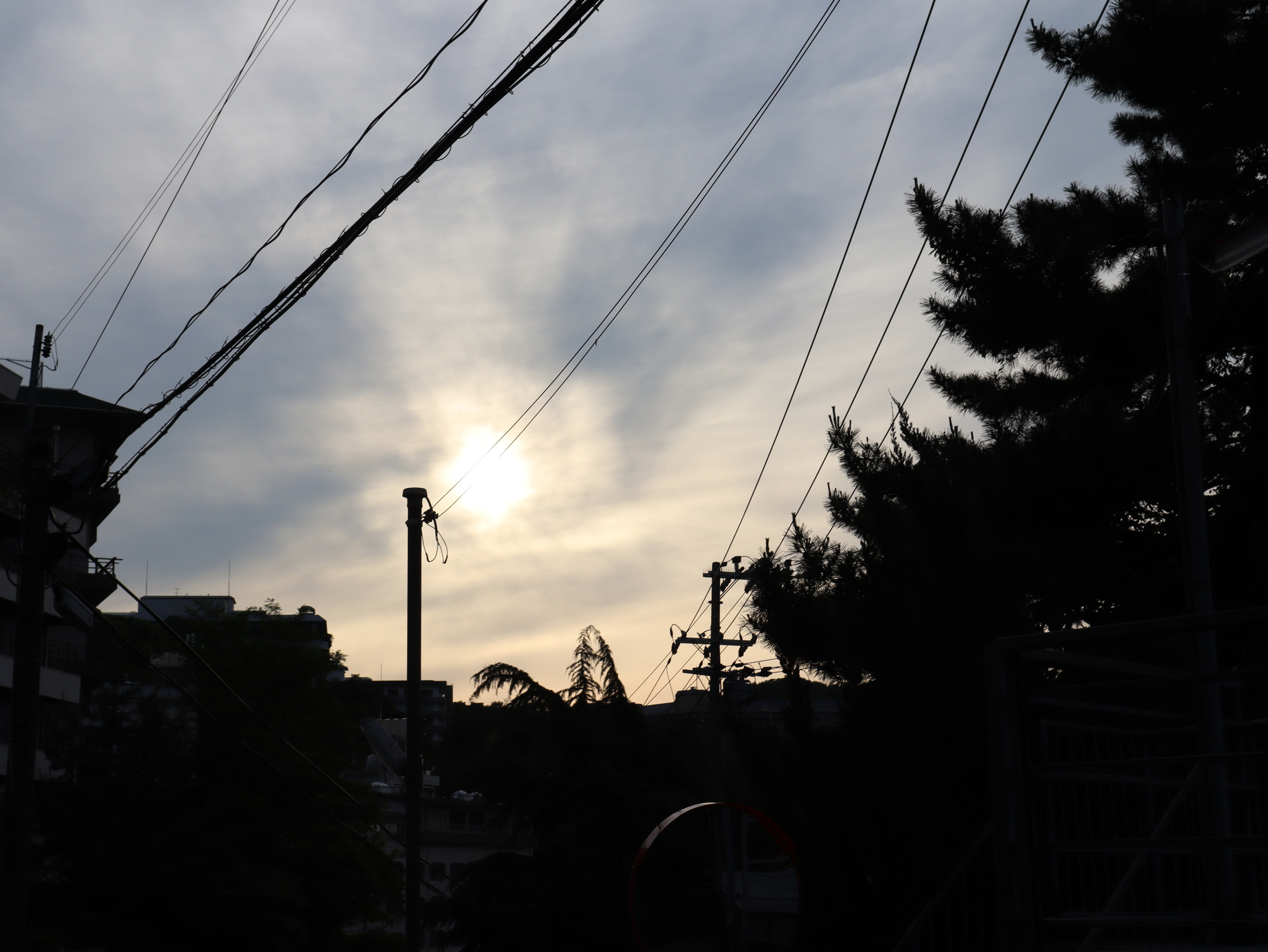 有马傍晚的天空，太阳藏在云后，电线与树影横过画面