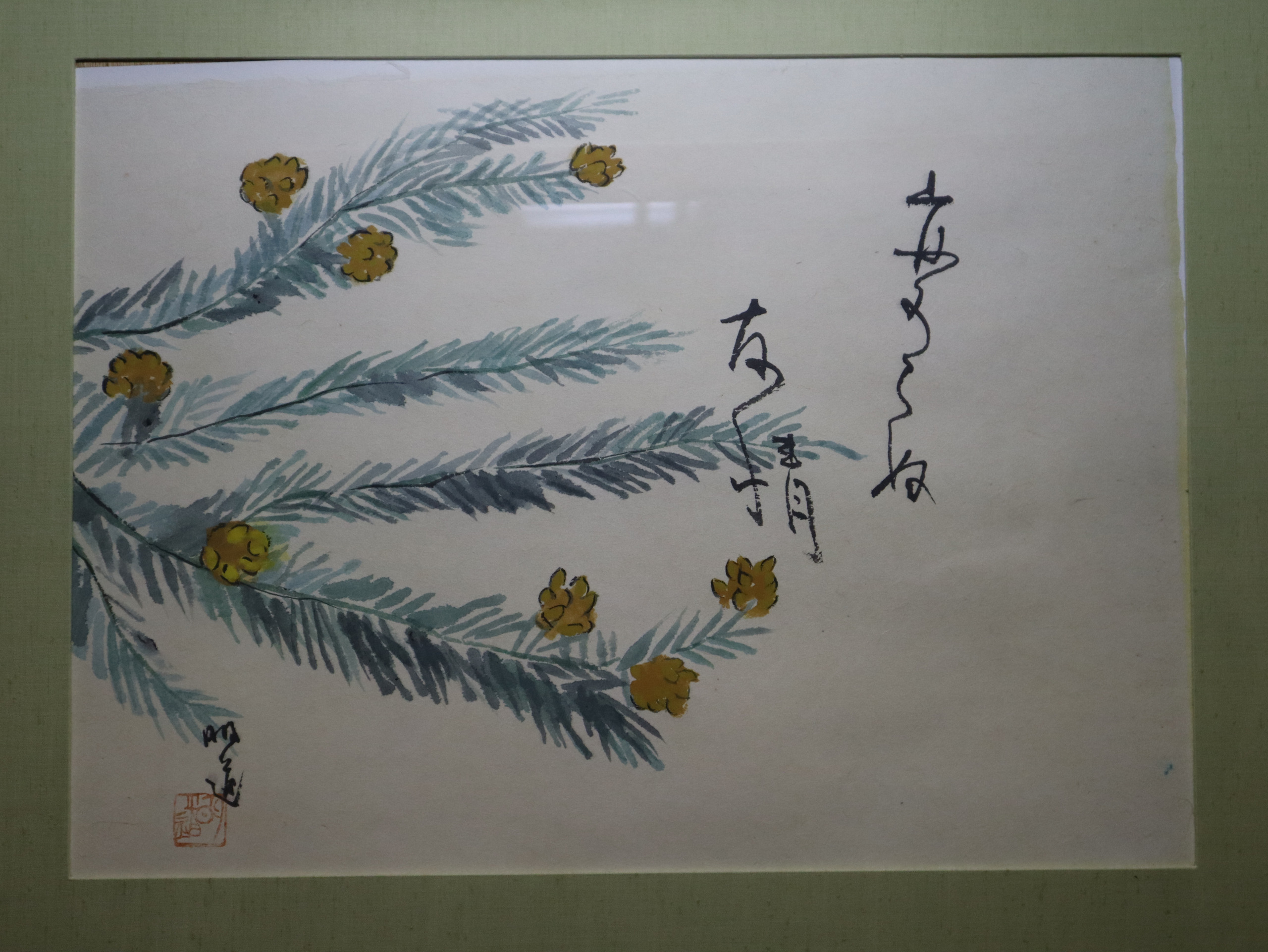 住处装框的花草画，青绿色枝叶间点着黄色小花，旁边有竖写题字