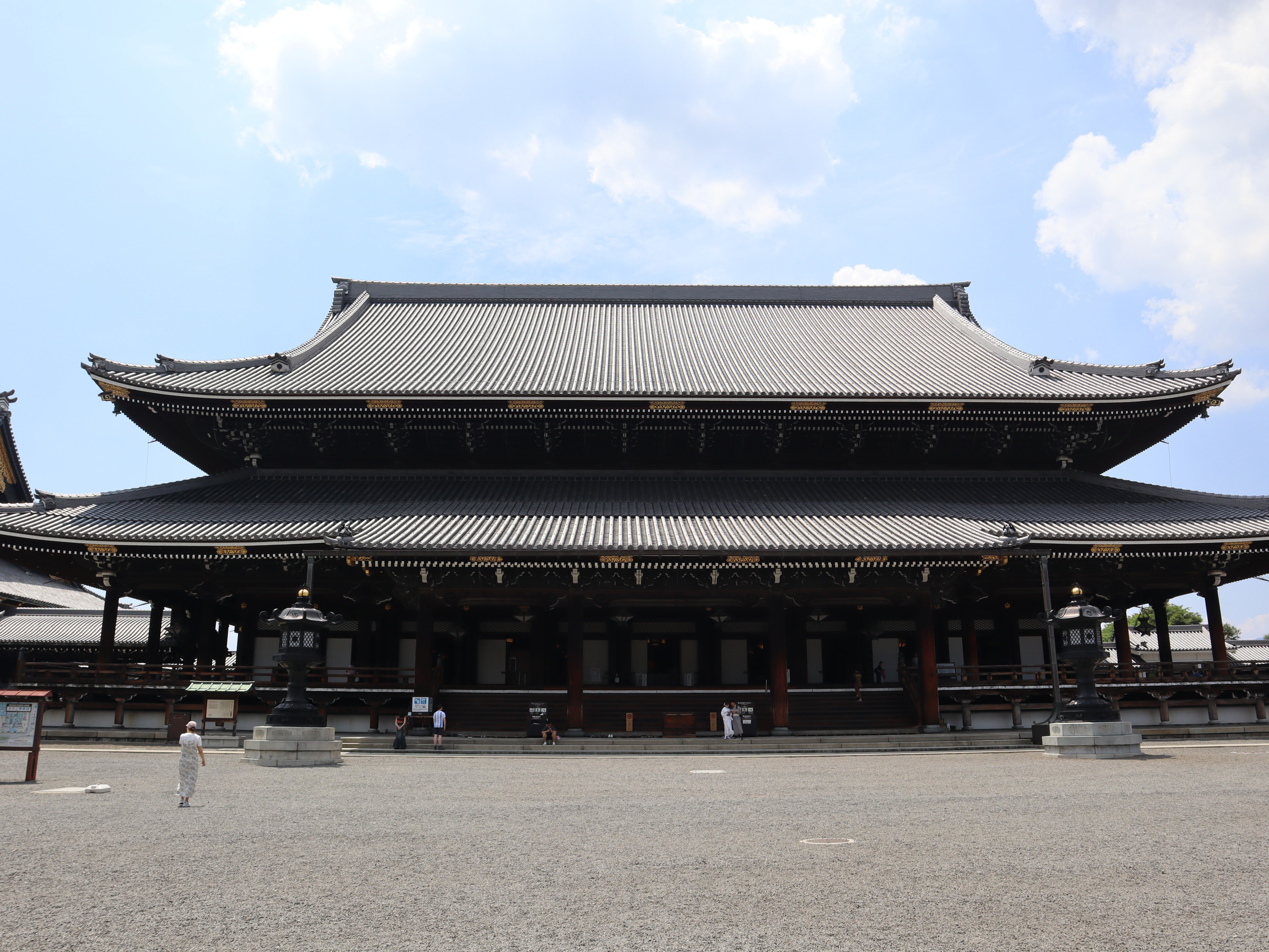 东本愿寺境内宽阔的砂石空地与殿堂，游人在屋檐下显得很小