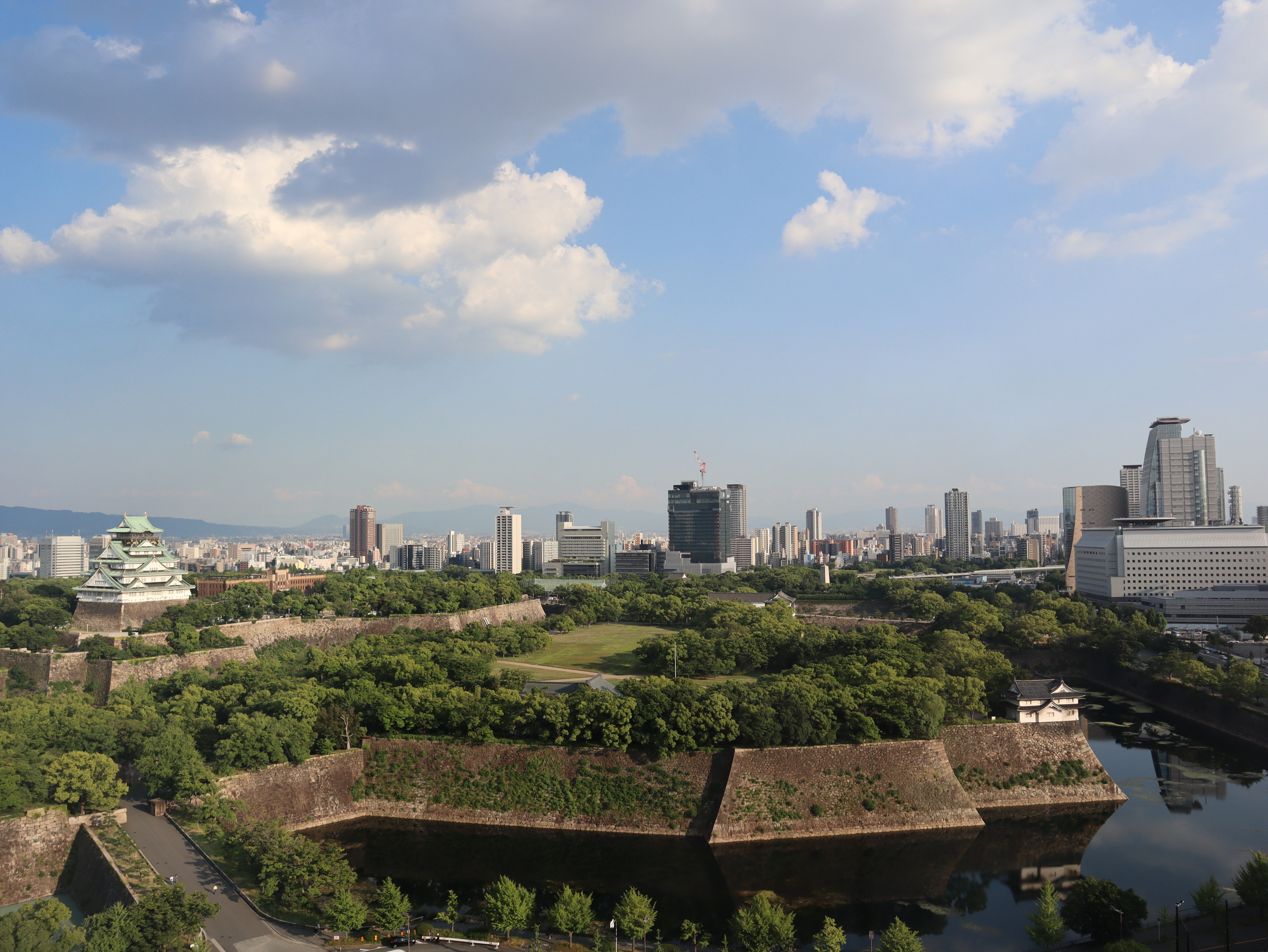 傍晚从高处望向大阪城,护城河、石垣、树林与城市楼群铺开