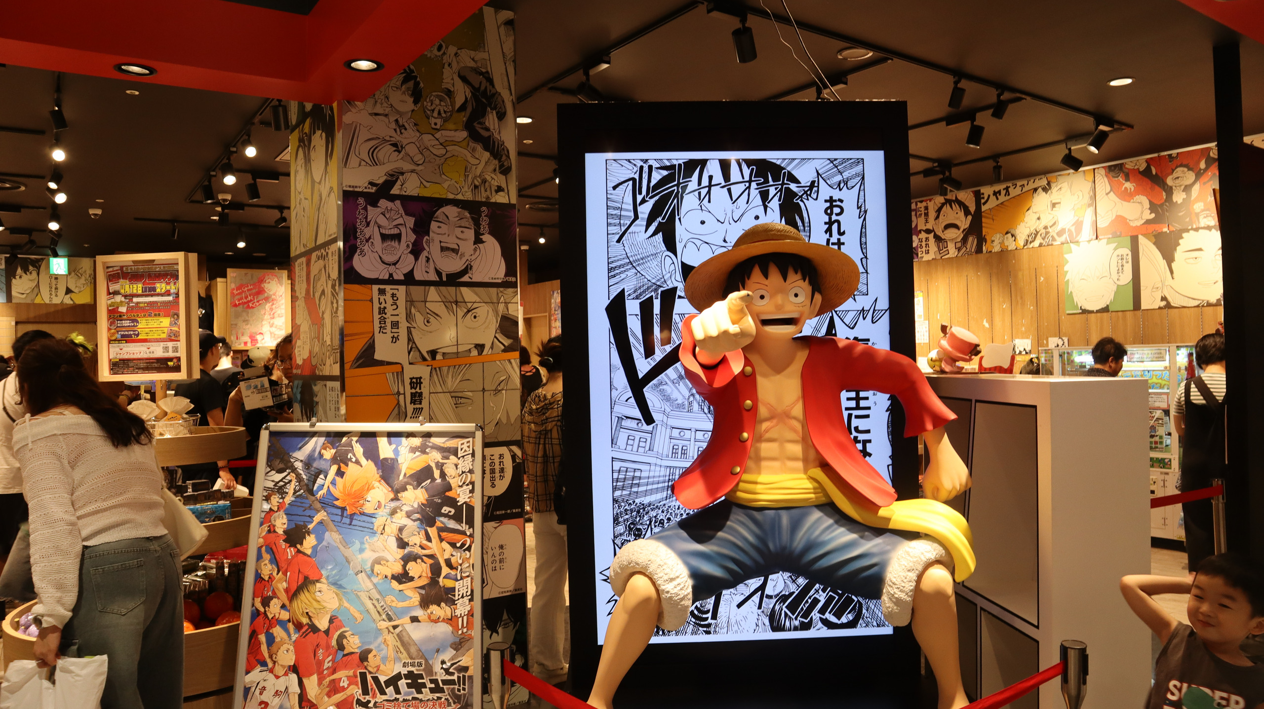 《海贼王》主题店面中的路飞塑像,周围墙面铺着漫画分镜