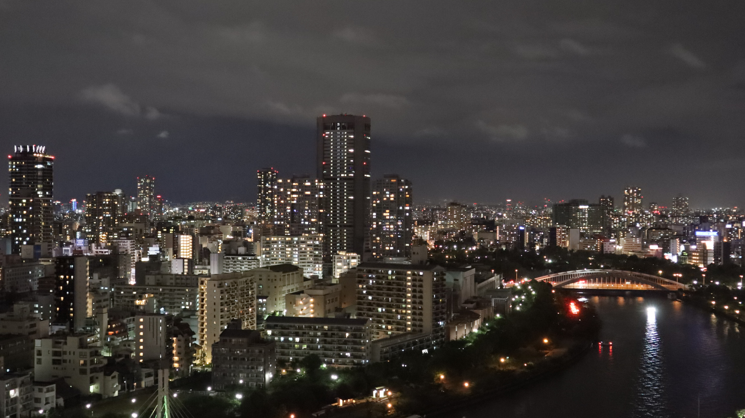 夜色中的大阪河道、暖光桥梁与两岸楼群,灯光在水上拖出倒影
