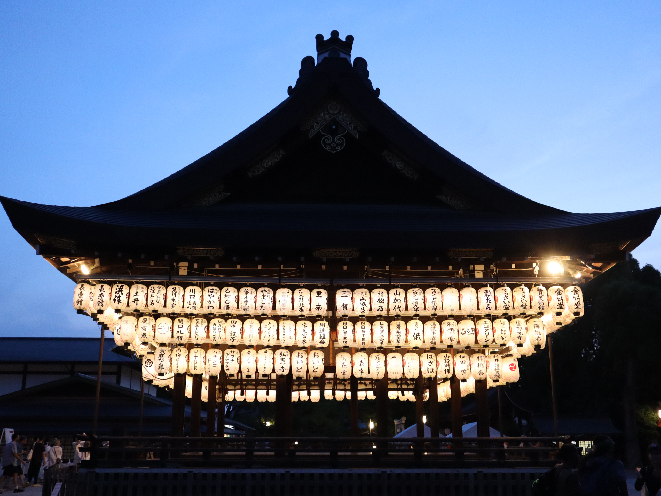 蓝色暮空下的八坂神社舞殿，成排白色灯笼亮起