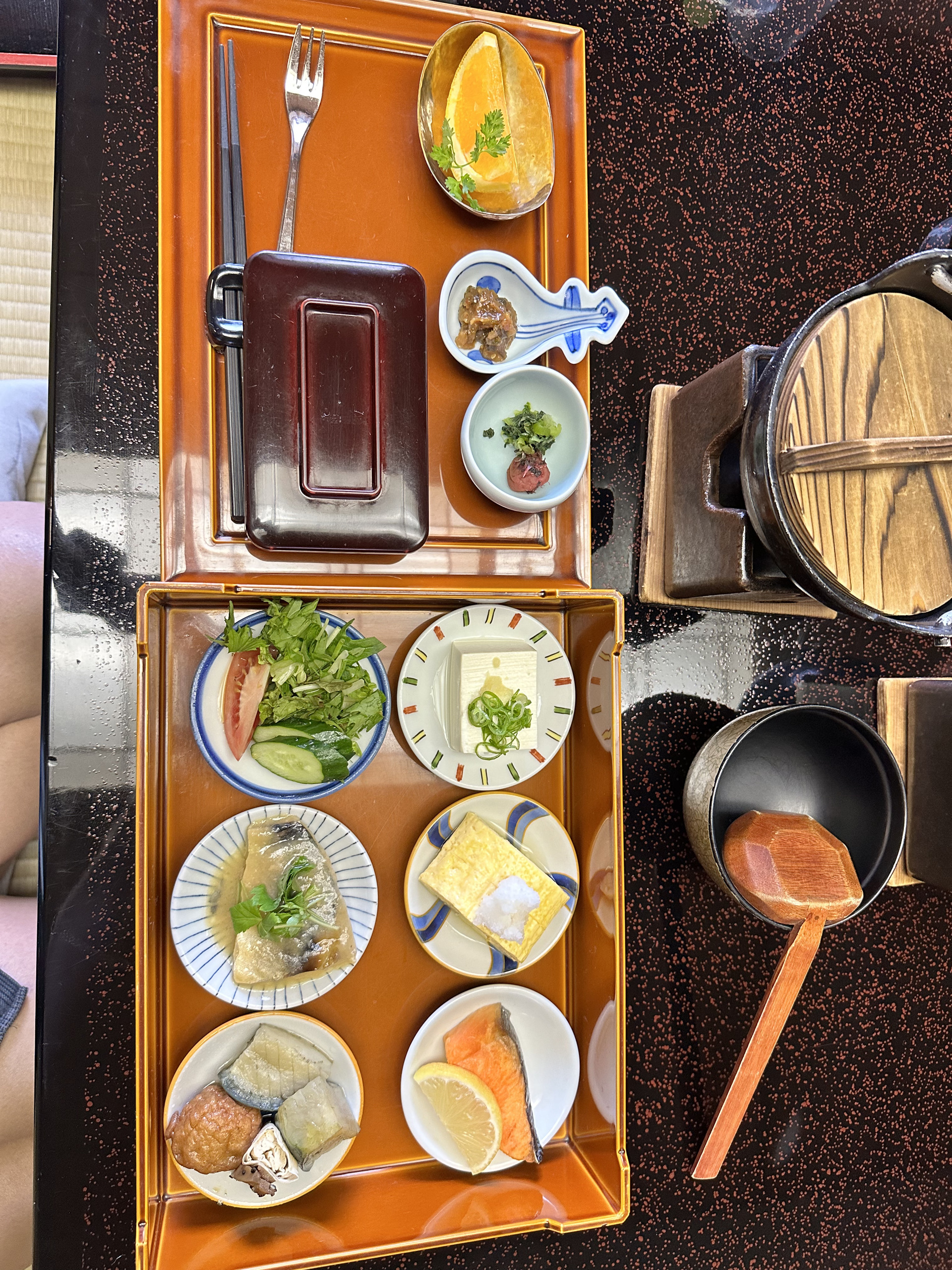 有马早餐的两个橙色托盘,分别摆着鱼、煎蛋、豆腐、蔬菜与水果